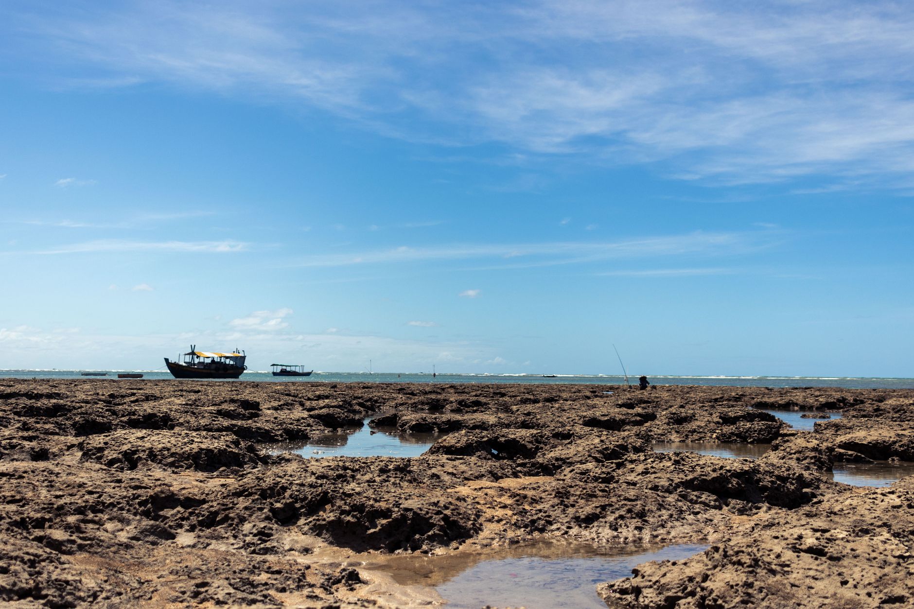 A serene coastal scene in Morro de São Paulo, Brazil, showcasing boats and rocky shoreline.