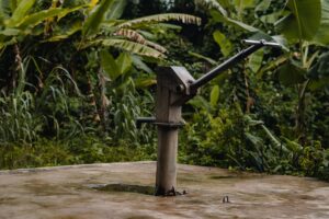 A rustic hand pump surrounded by dense jungle foliage, showcasing the harmony of human and nature.