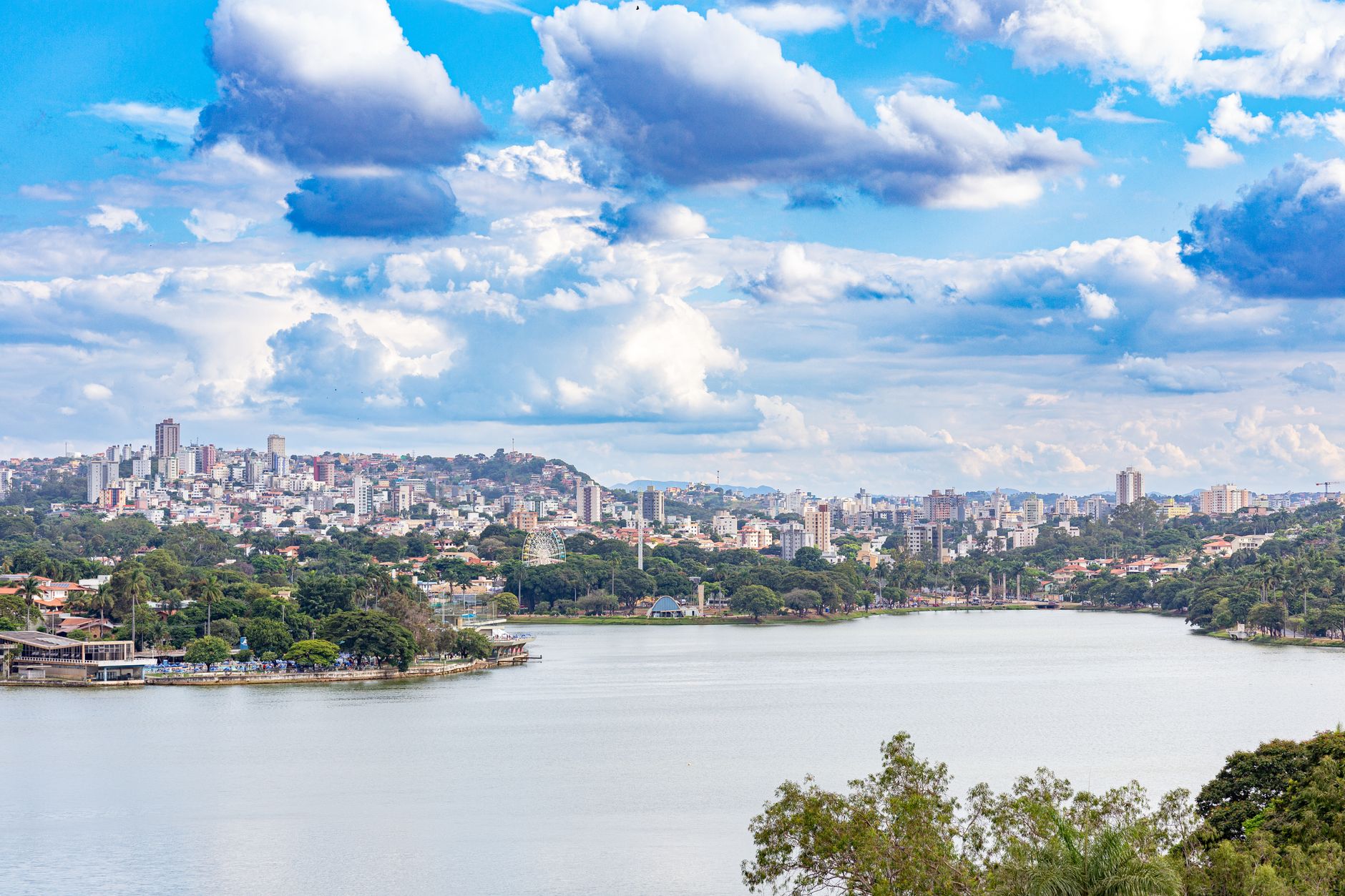 Stunning panoramic view of Belo Horizonte skyline over a serene lake under a vibrant sky.