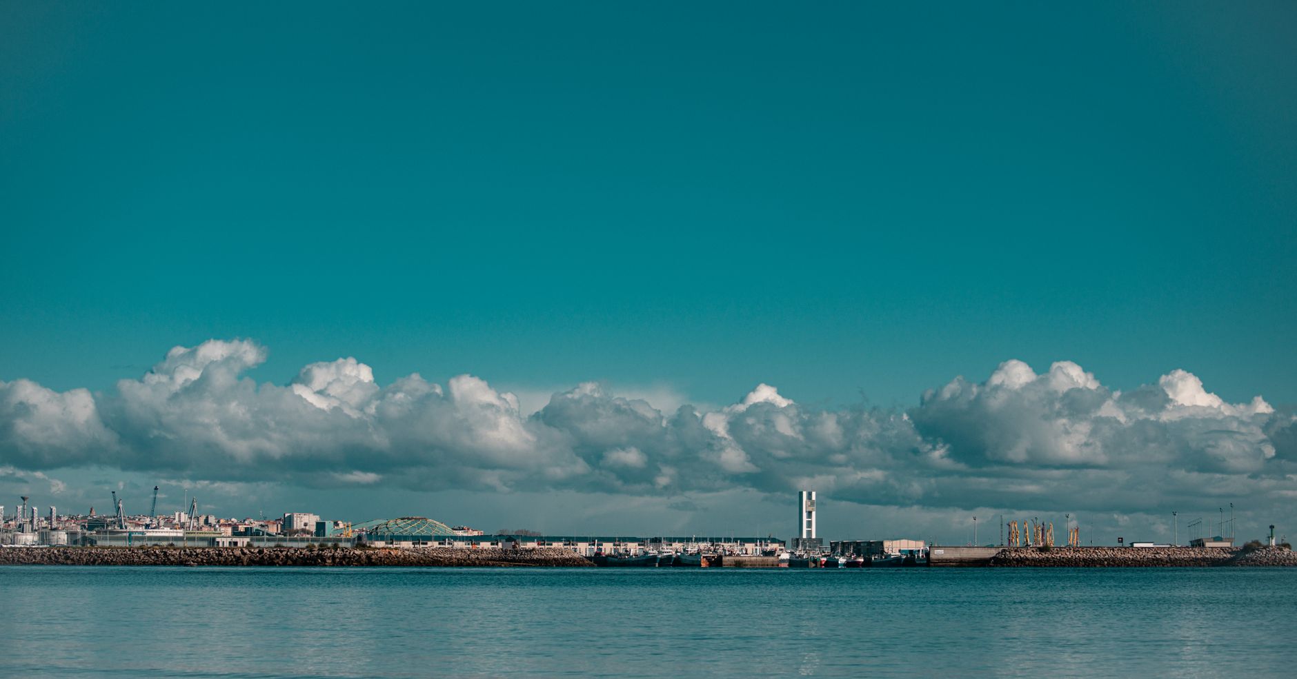 A scenic view of a coastal cityscape with fluffy clouds and calm sea.