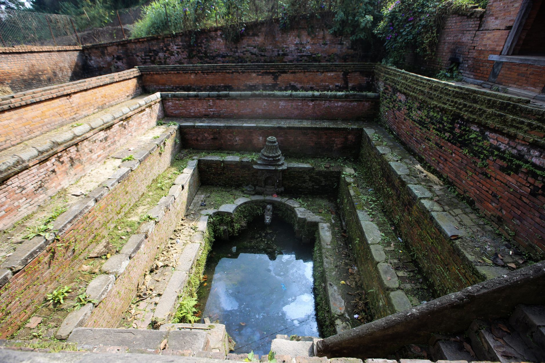 Explore the historical architecture of an ancient water well in Kathmandu, showcasing stone craftsmanship.