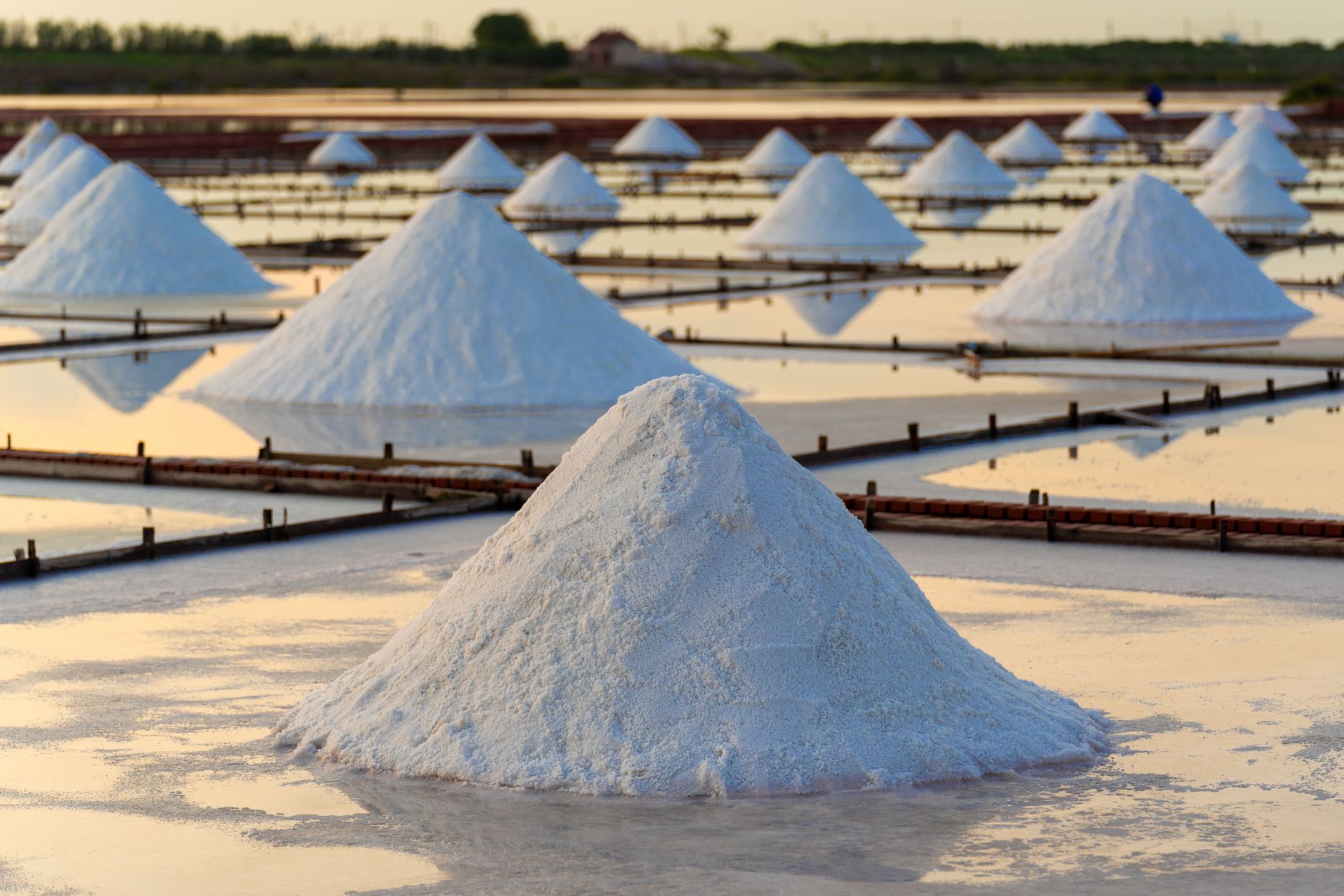 Scenic view of salt piles reflecting sunlight on Tainan's salt flats, capturing traditional salt production process.