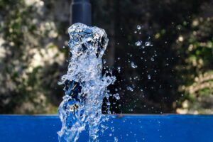 Close-up of water splashing from a fountain with droplets frozen in motion against a blurred outdoor background.