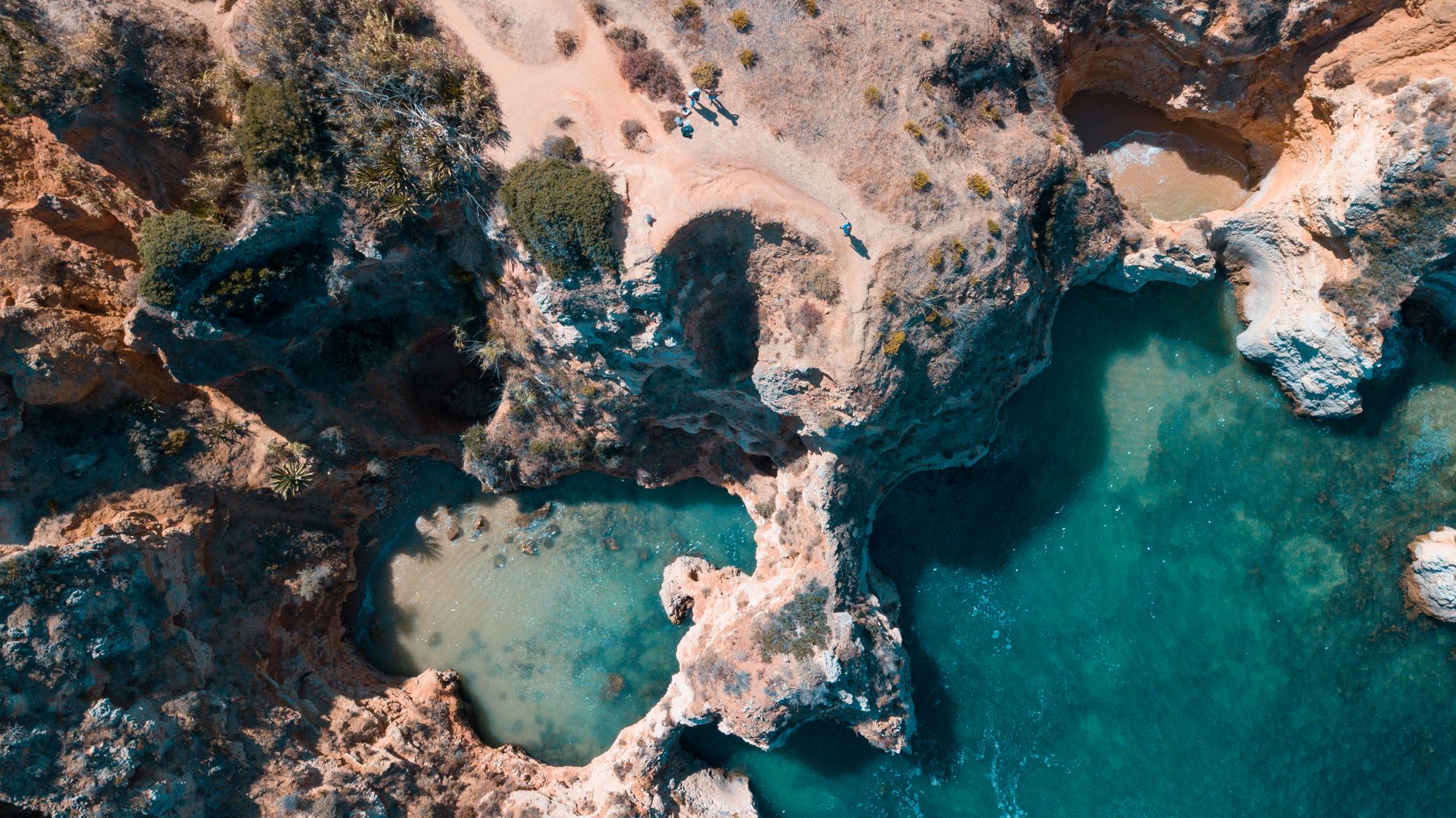 Stunning aerial shot of a rocky coastline with vibrant blue waters.