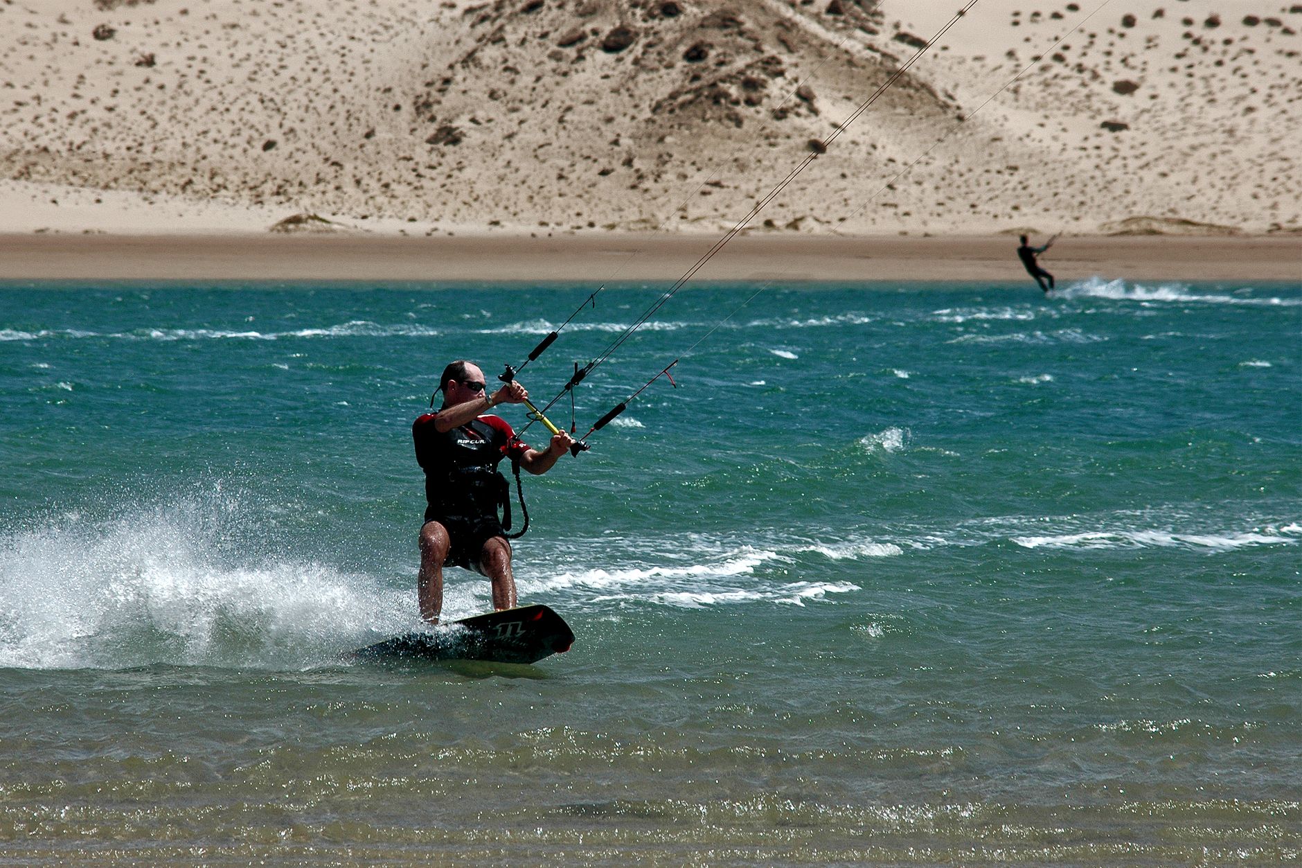 A thrilling kitesurfing scene at the beach in Oued Ed-Dahab-Lagouira, featuring waves and dunes.