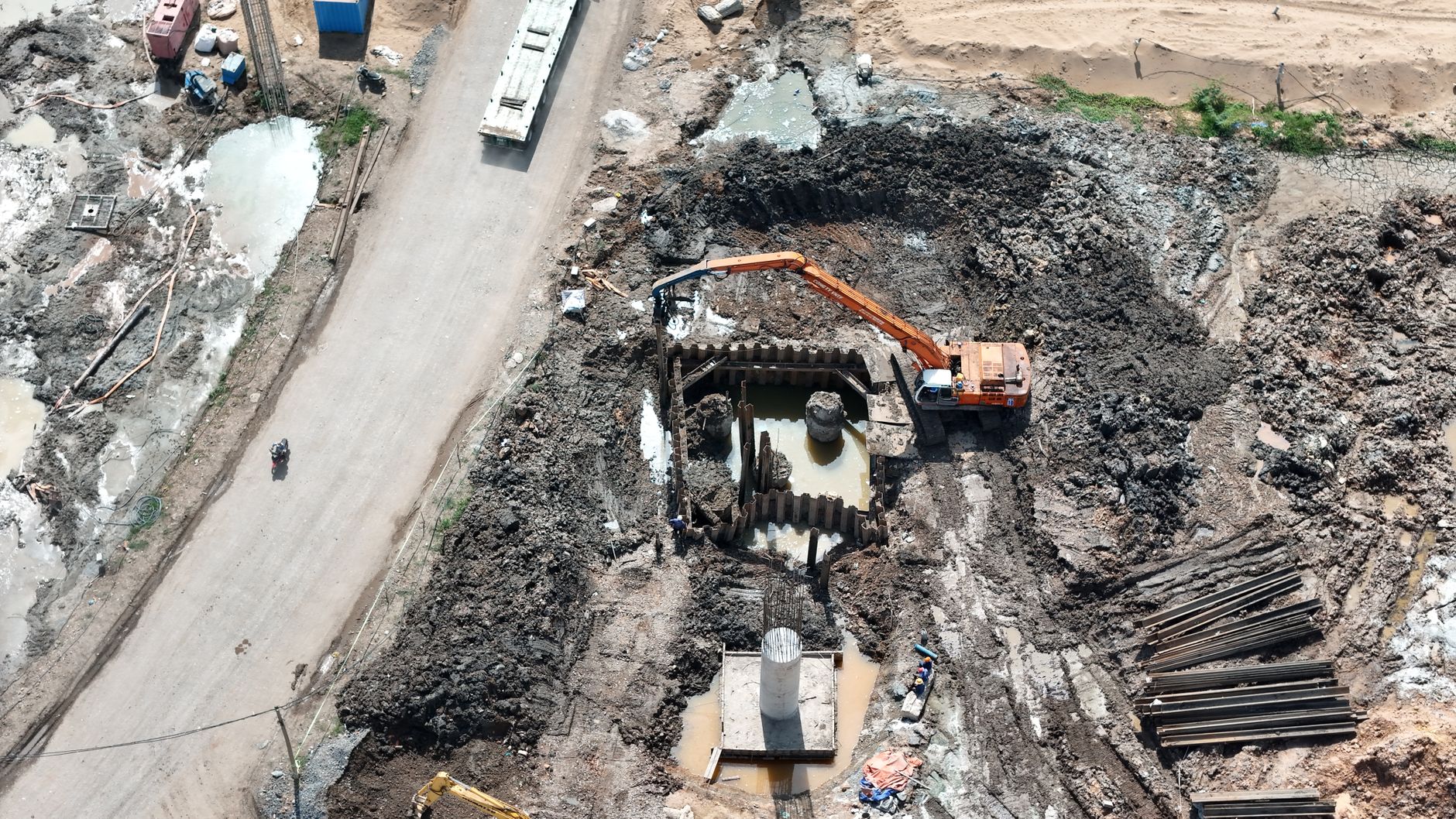 Top view of construction site showing an excavator working in muddy terrain.