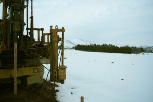 A large industrial drill machine set against a snowy winter landscape with mountains in the background.