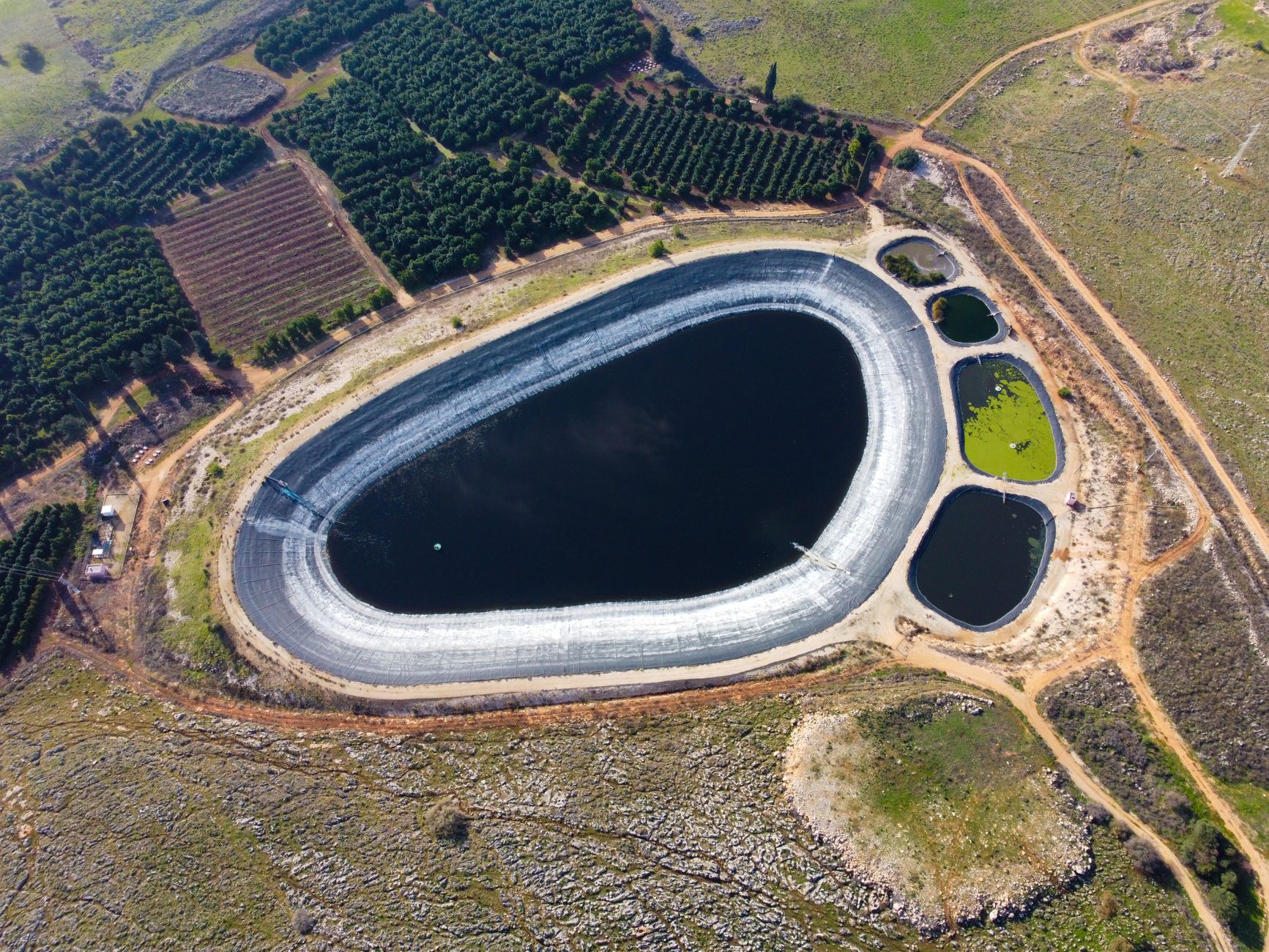 Aerial shot of a reservoir and farmland showing irrigation ponds and planted fields.