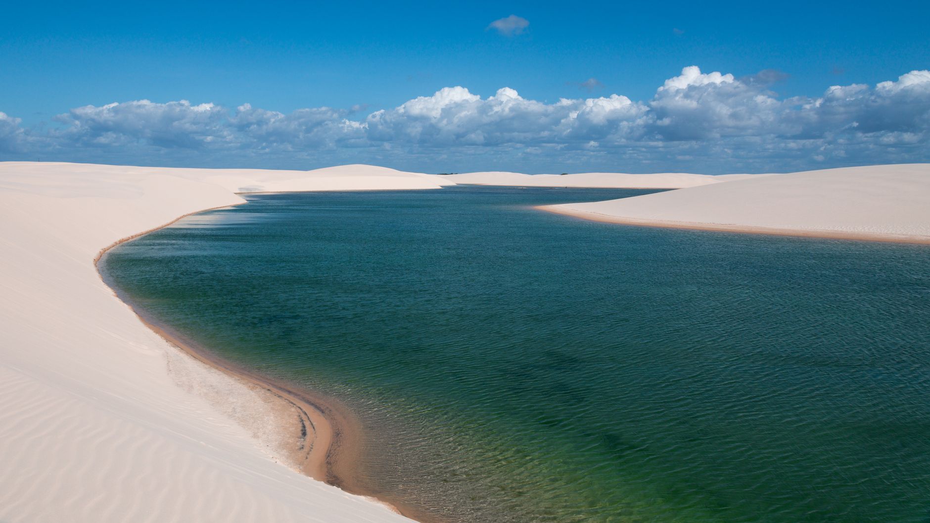 A breathtaking aerial shot of Lençóis Maranhenses' sand dunes and turquoise lagoon in Brazil.