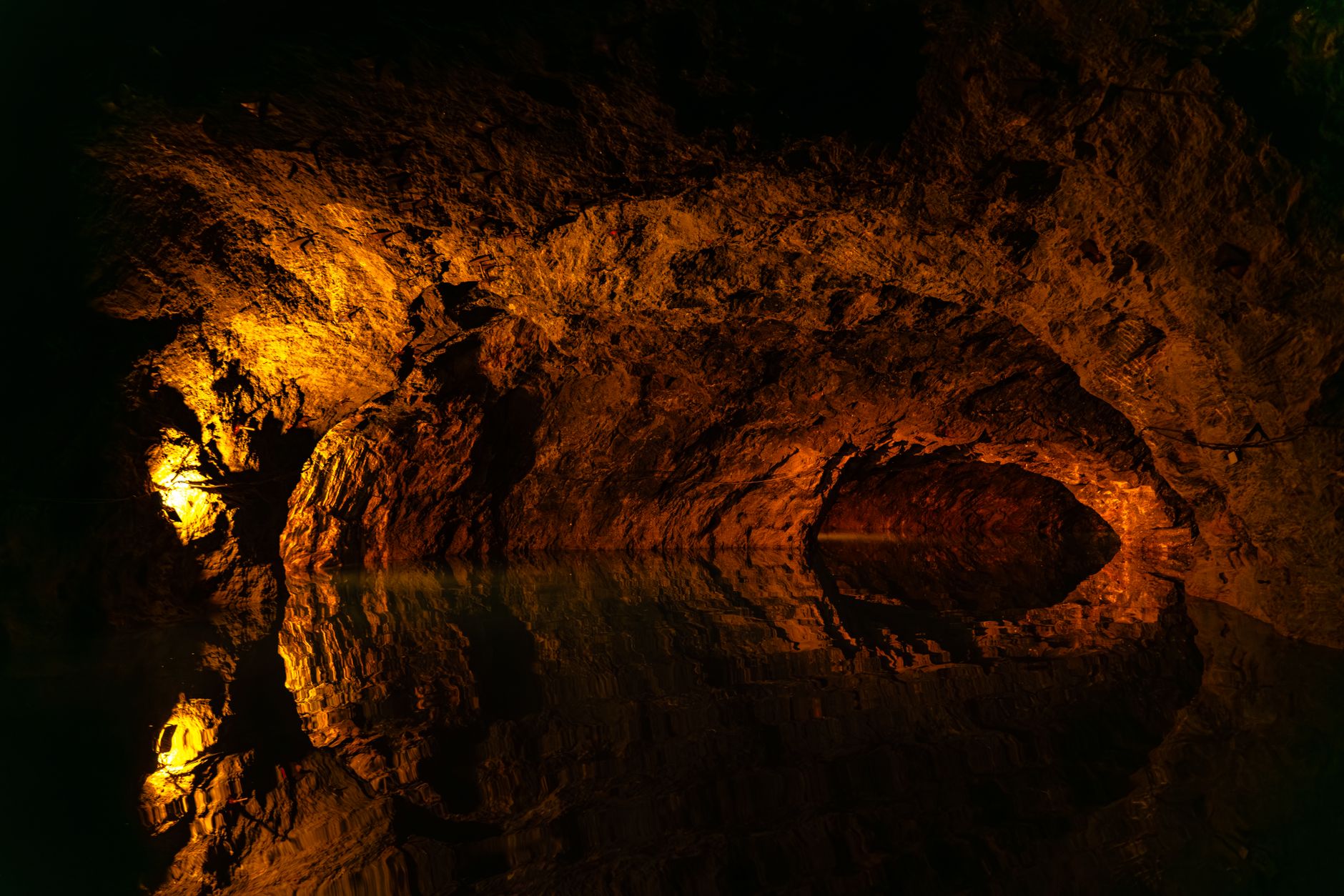 Explore a dimly lit cave in Austria with stunning water reflections.