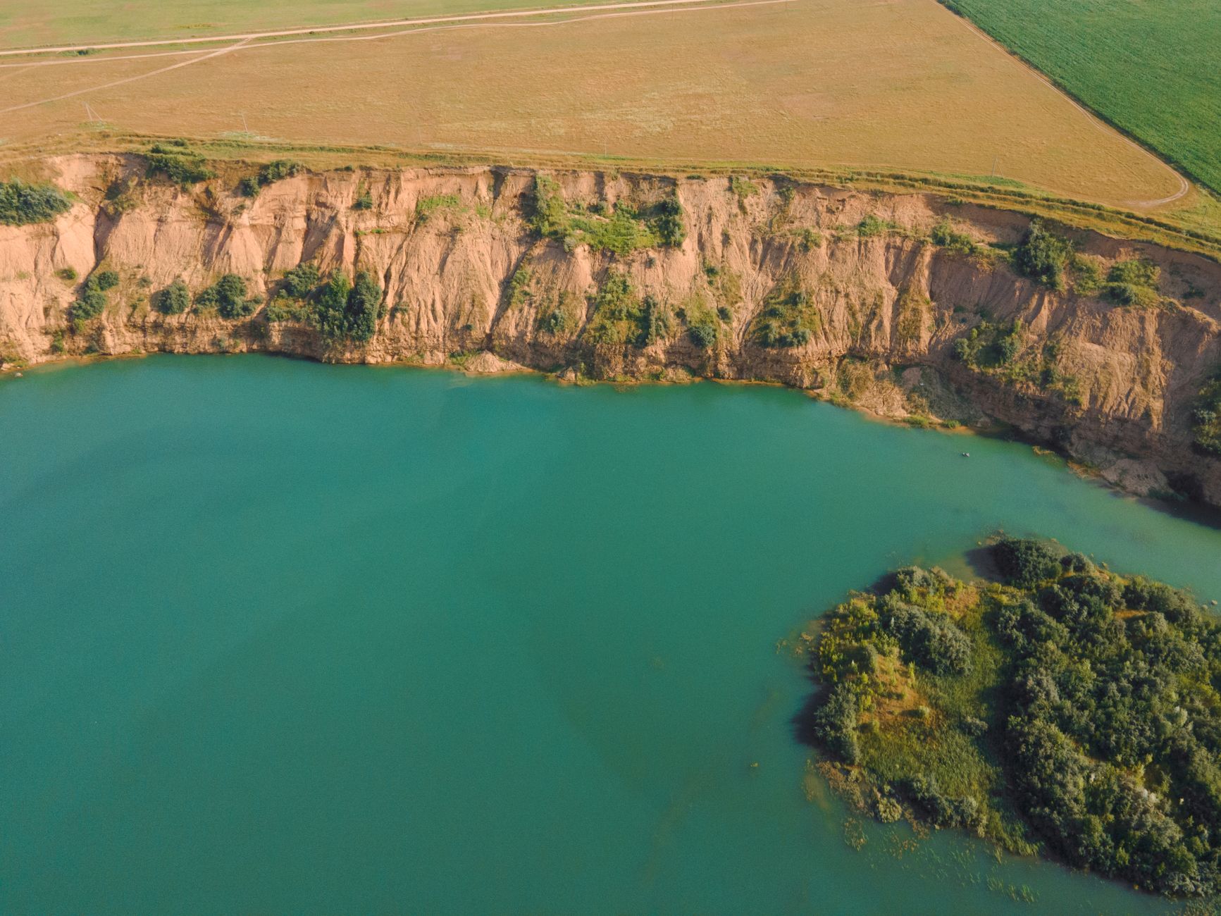 A stunning aerial shot of a tranquil lake bordered by cliffs and rolling cropland.