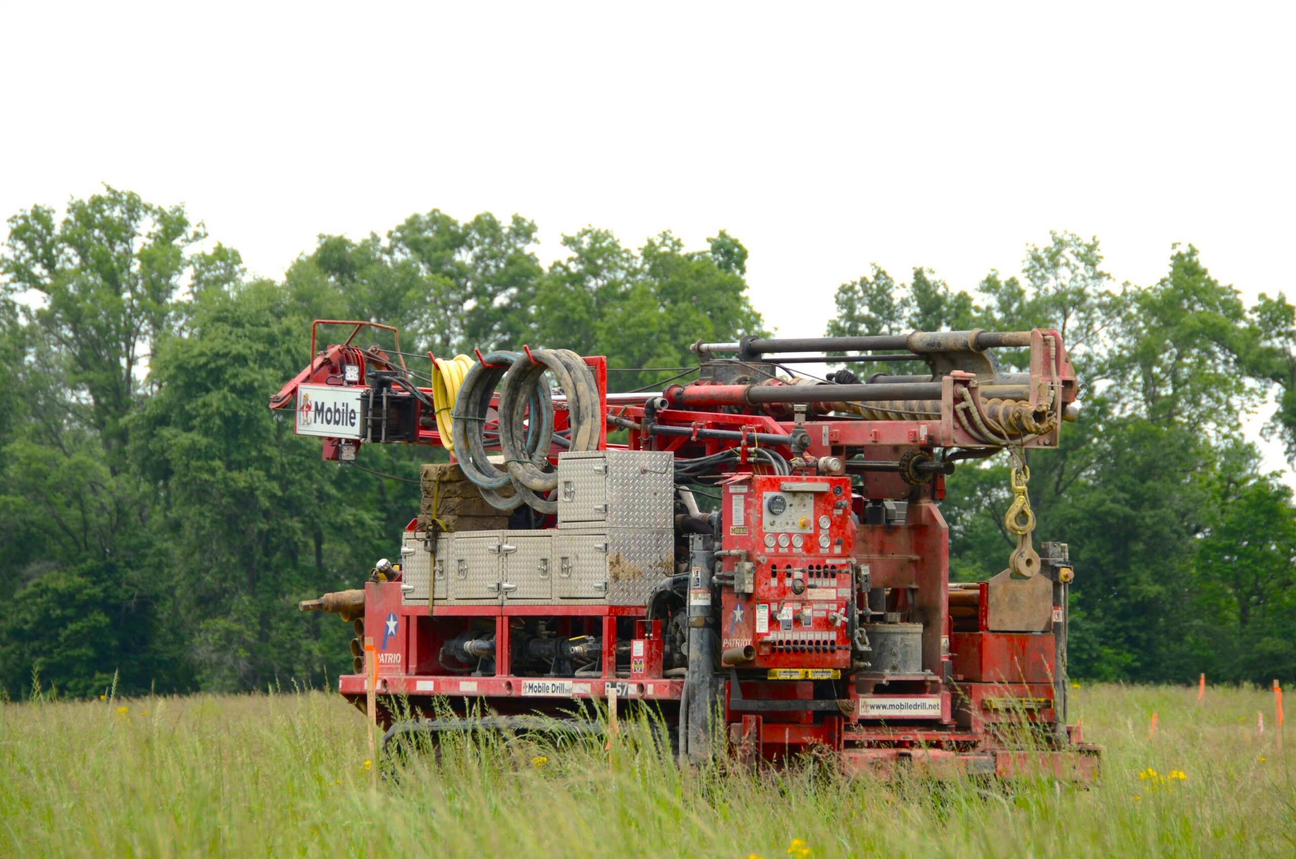 A drilling rig is set up in a grassy field