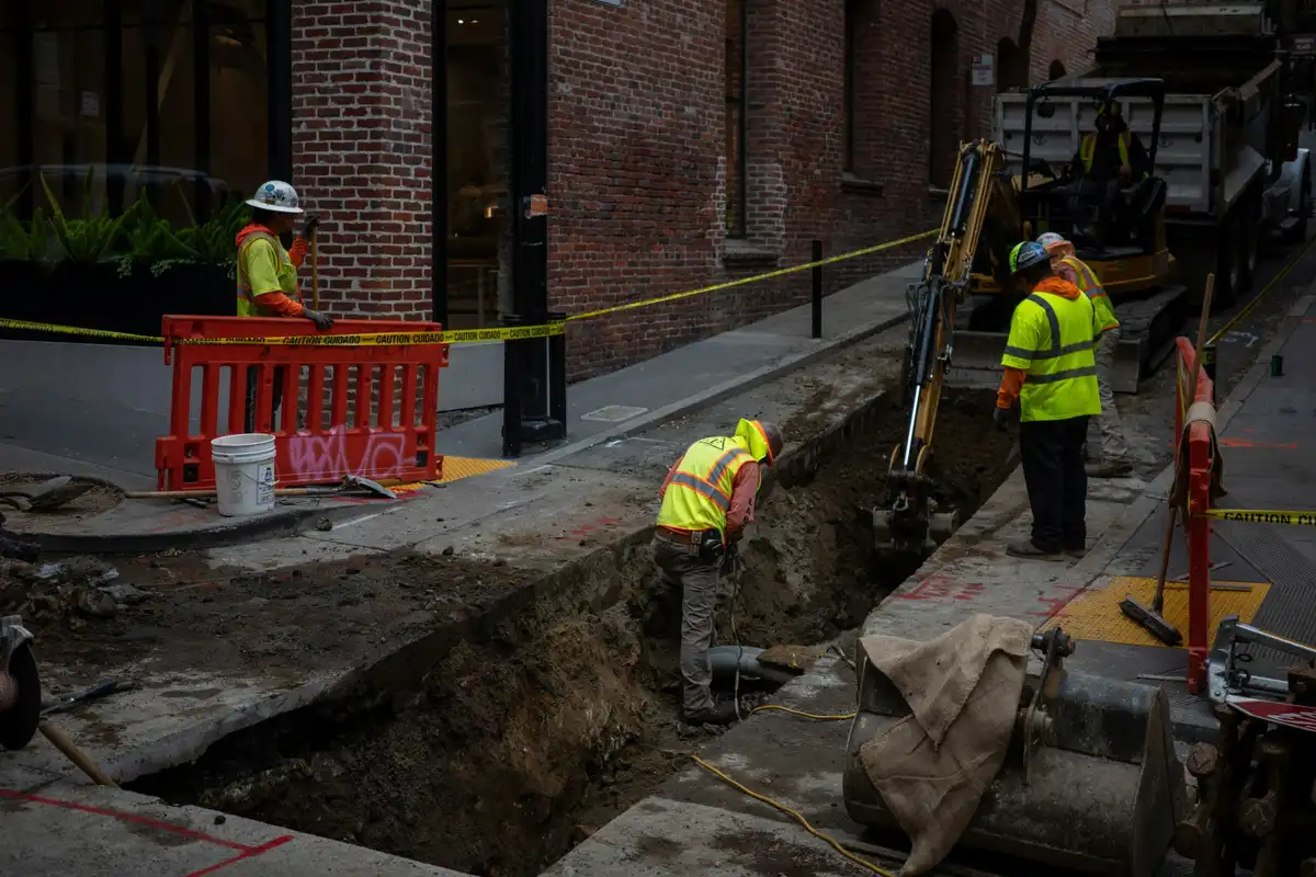 Construction workers digging a trench on a city street